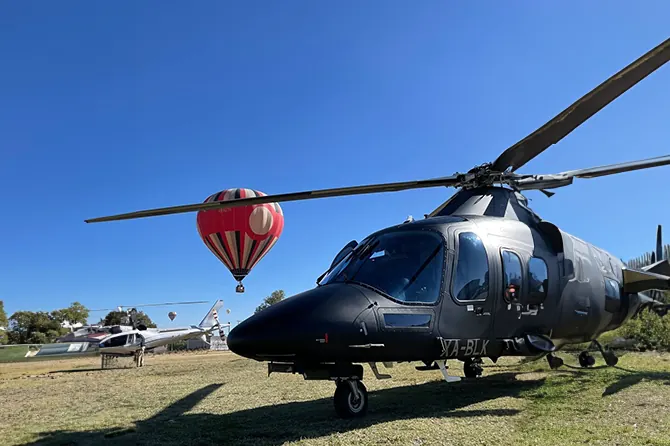 AgustaWestland AW109 negro con un globo aerostático al fondo