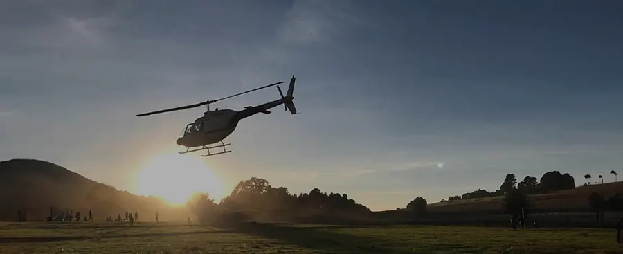 Silueta de un helicóptero de HeliStar al atardecer sobre las montañas